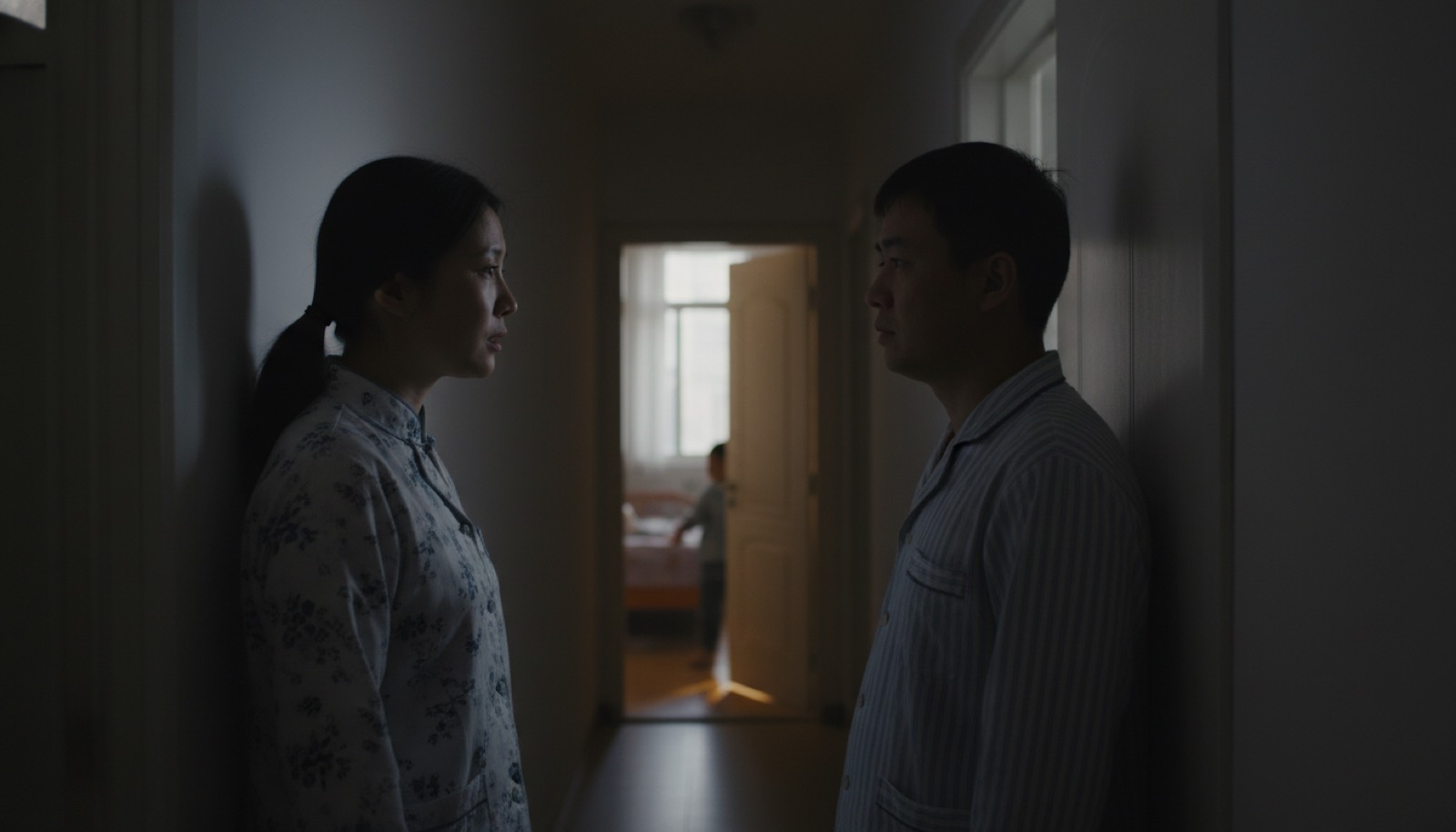 夜晚走廊夫妻压低声音说话远处孩子卧室透光