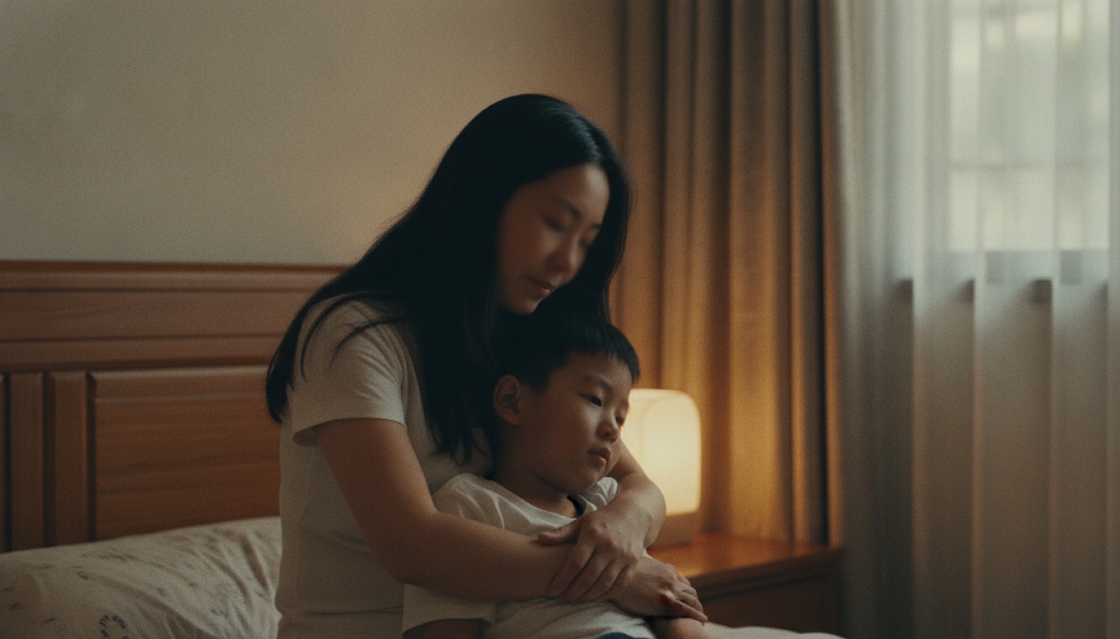 傍晚卧室妈妈把男孩搂在怀里轻拍安抚