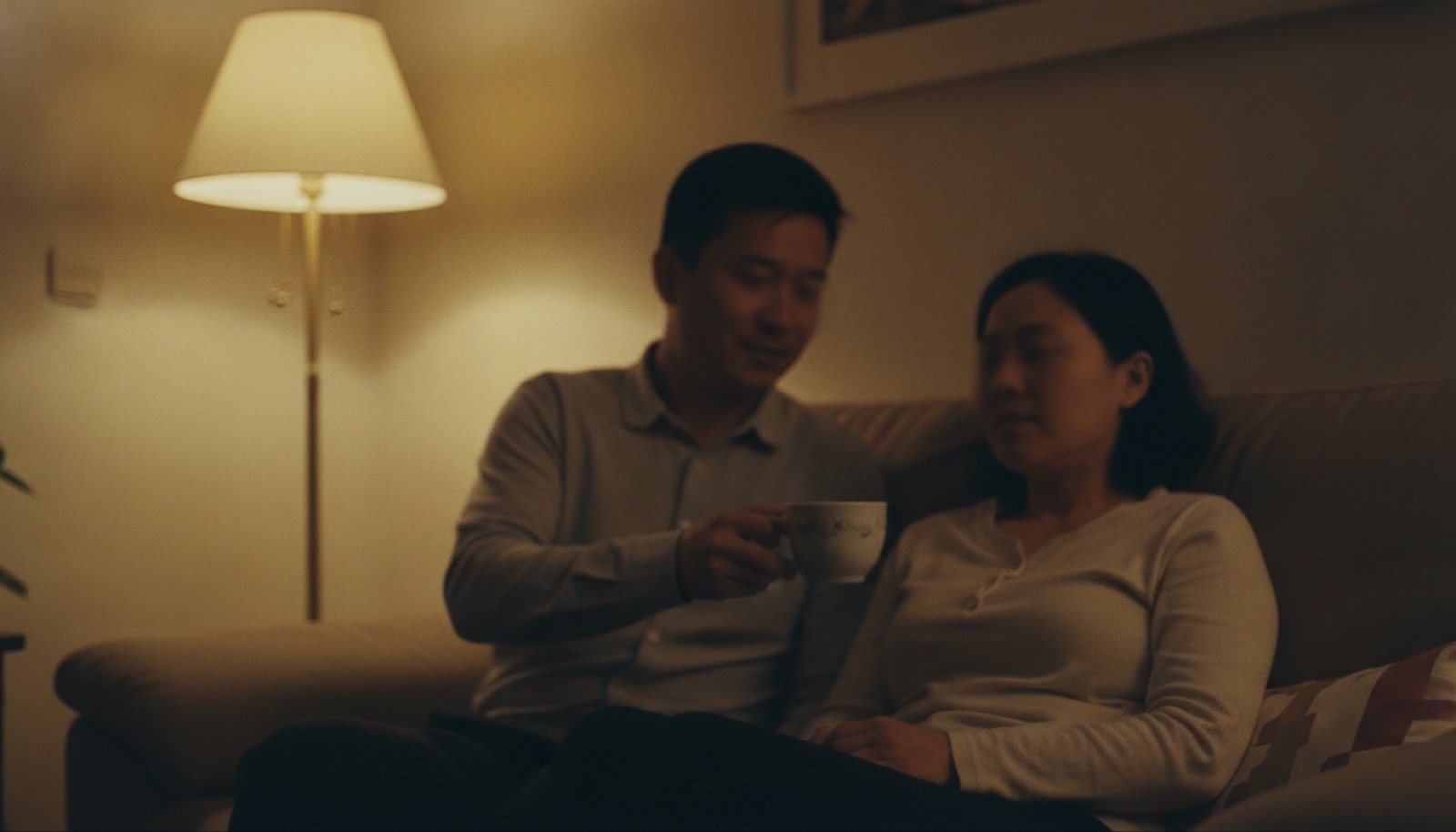 夜晚客厅爸爸给妈妈递热茶妈妈神情松了一点