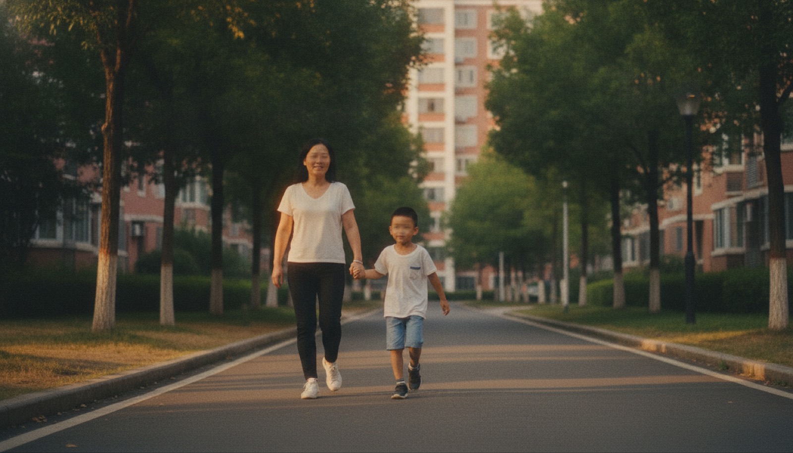 傍晚小区步行道妈妈牵孩子散步孩子轻快走妈妈平静